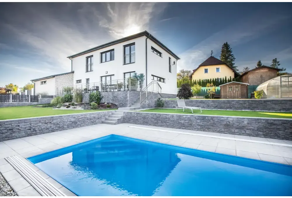 Modernt tvåvåningshus i vitt med sten och fönster samt Thermopp poolpaket Qbig